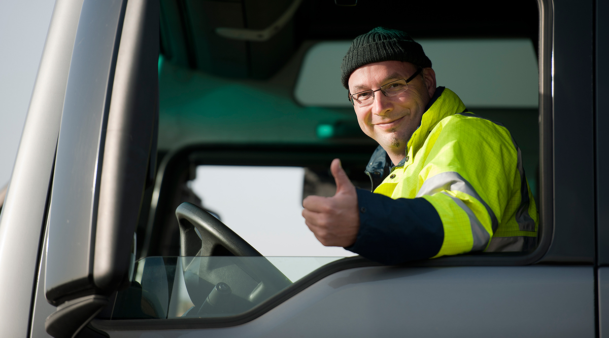 Truck driver in hi-vis vest standing in front of a modern white semi-truck